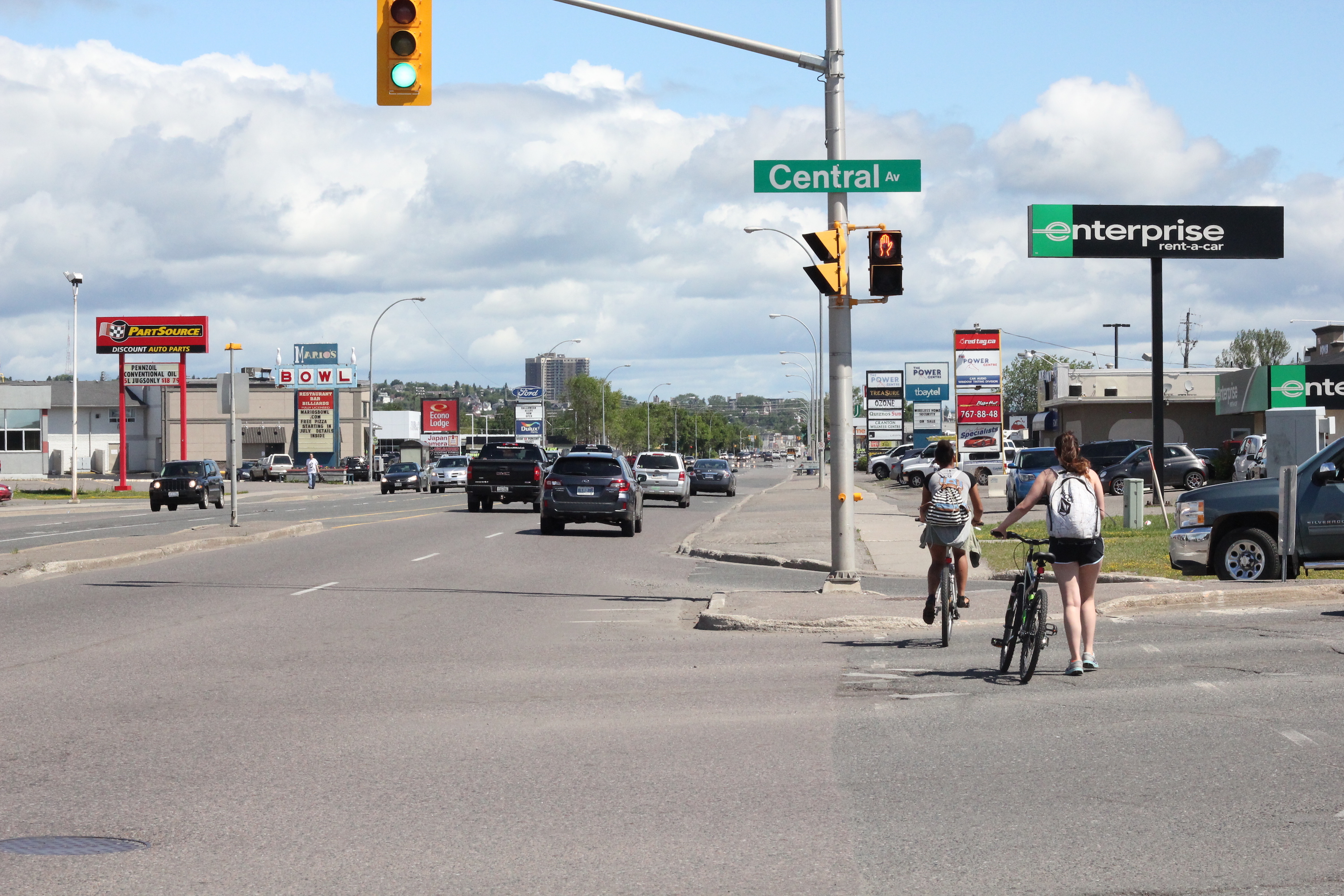 Two women cross Central Avenue on their bikes while riding on the sidewalk